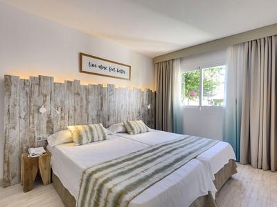 Gemütliches Schlafzimmer mit rustikalem Holz-Panel, Doppelbett und hellem Vorhang am Fenster.