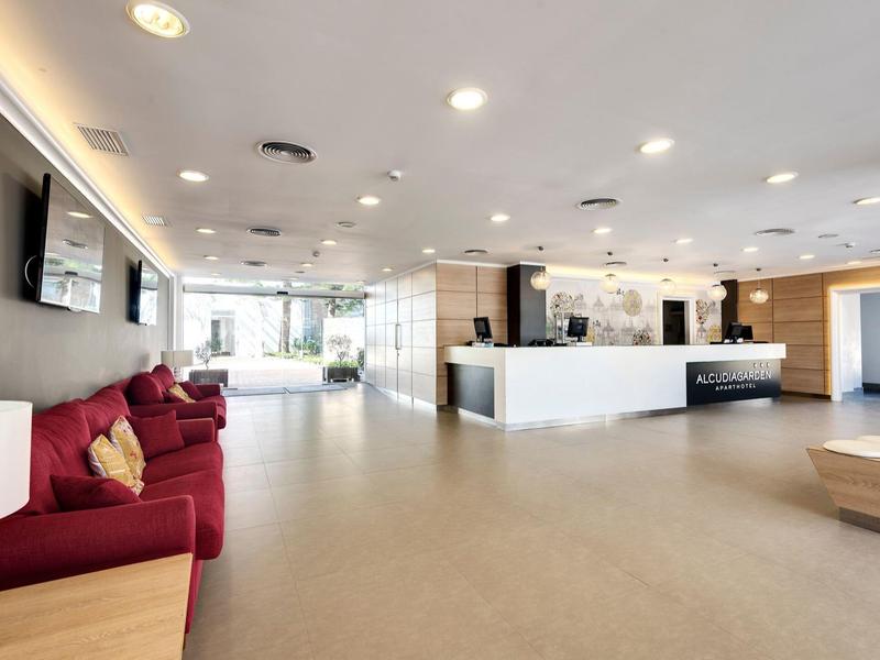 Przestronny nowoczesny hol hotelowy z czerwonym sofą i jasną recepcją.