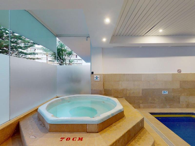 Nowoczesne jacuzzi w jasnej, eleganckiej strefie wellness z basenem i drewnianymi panelami.