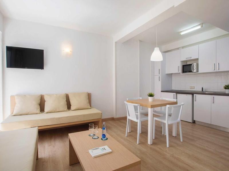 Bright, modern apartment with sofa, dining table, chairs and kitchenette.