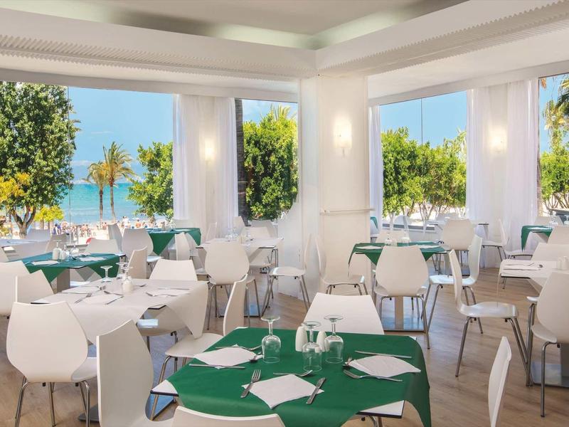 Bright dining room with sea view and surrounded by trees.
