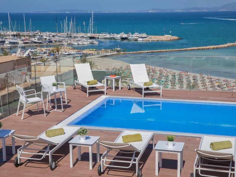 Pool area with lounge chairs overlooking the sea and marina.