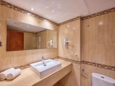 Moderner Hotelbadezimmer mit großem Spiegel, Waschbecken, Haartrockner und Handtüchern.