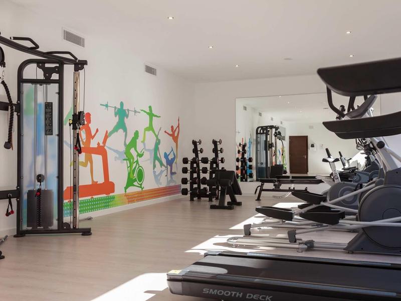 Palestra moderna con tapis roulant, pesi e murales colorati.