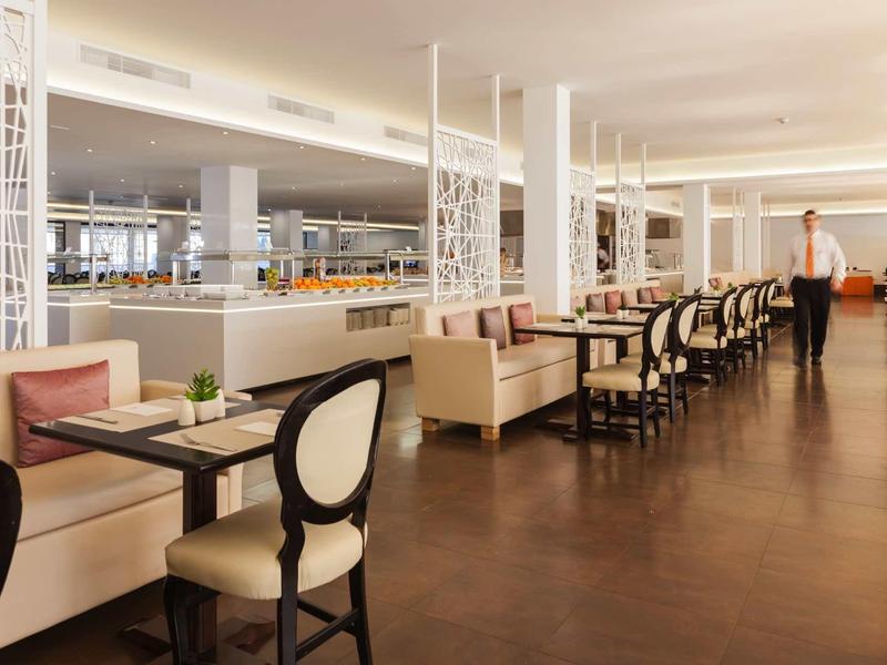 Area ristorante elegante in hotel con tavoli, sedie e panche imbottite.