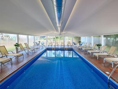 Overdekt zwembad met houten vloer en ligstoelen aan beide zijden