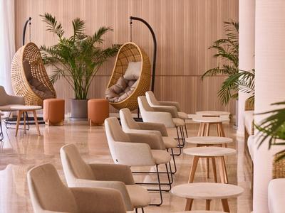 Moderner Hotel-Loungebereich mit hängenden Körbchenstühlen, bequemen Sesseln und Pflanzen.