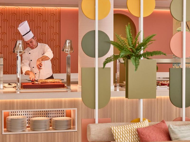 Chef in witte uniform bereidt gerecht in modern restaurant met warme sfeer.