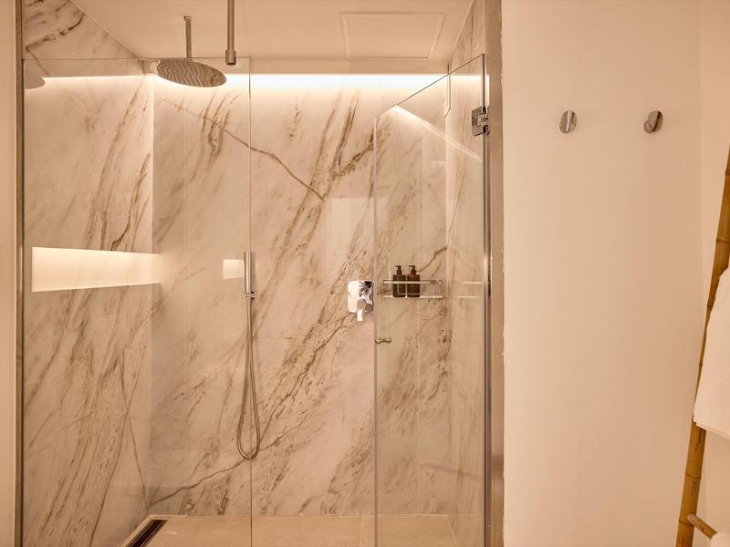 Moderne douche met glazen deur en marmeren muren in een hotelbadkamer