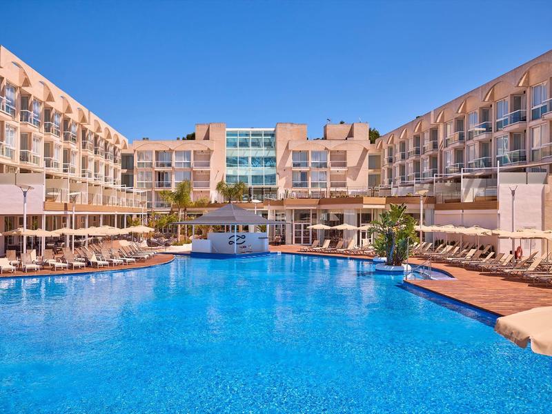 Groot zwembad voor modern hotel onder heldere lucht.