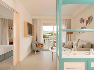 Jasny pokój hotelowy z balkonem, wygodną sofą i nowoczesnym wnętrzem.