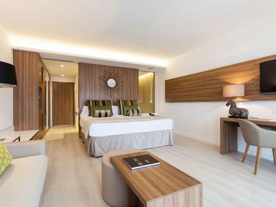 Helles Hotelzimmer mit Doppelbett, Holzvertäfelung und modernem Schreibtisch.