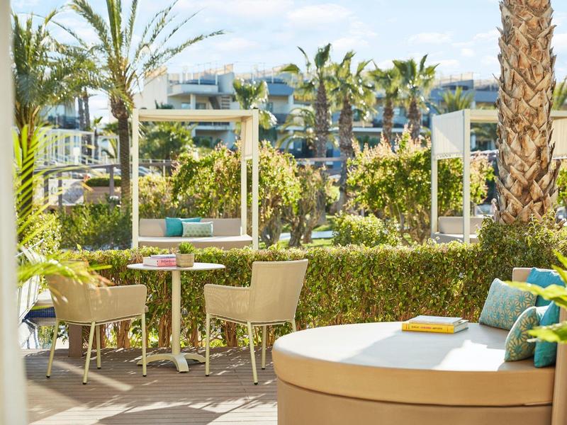 Cozy terrace with chairs, tables, and palm trees in a hotel garden