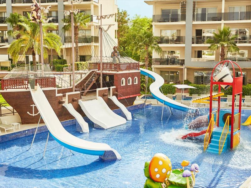 Colorful water slide and playground in pool in front of hotel buildings