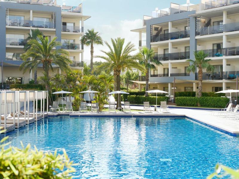 Modern hotel pool with lounge chairs and palm trees under clear sky