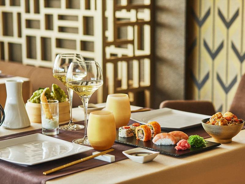 Elegant set table with sushi, candles, and wine glass in a modern restaurant.