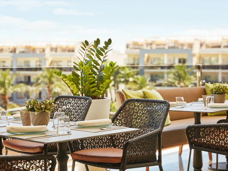 Modern outdoor seating area with chairs and tables on a terrace overlooking surrounding buildings