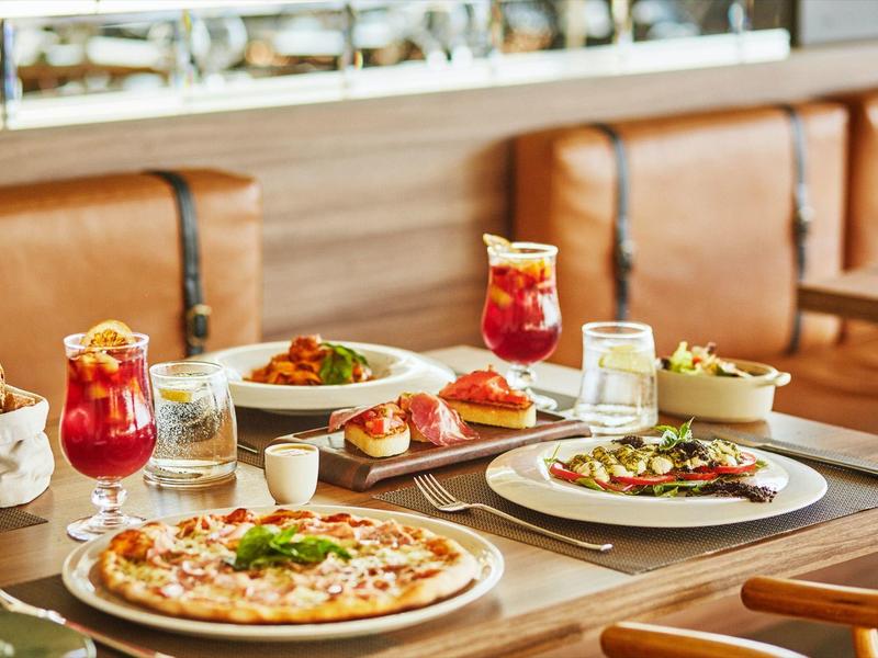 Table with pizza, bruschetta, salad, and drinks in a cozy restaurant.