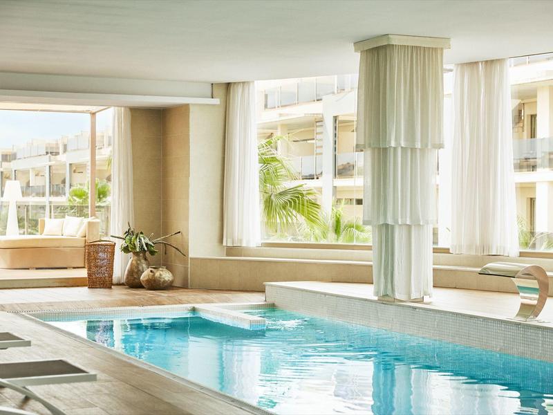 Indoor pool with large windows and plants, bright and inviting wellness atmosphere.