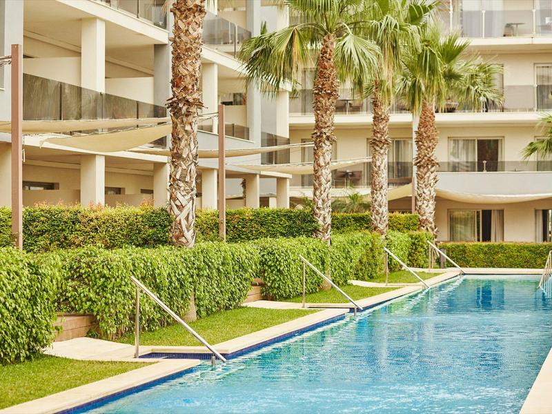 Swimming pool with palm trees and hotel building in the background