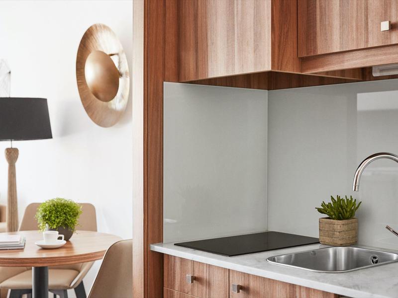 Modern kitchenette with sink, stovetop, and wooden cabinets in a living space.
