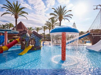 Children's pool with water slides and water features under palm trees on a sunny day
