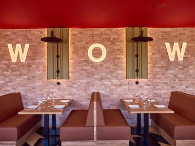 Modern restaurant corner with comfortable brown booths and WOW wall decor on brick wall.