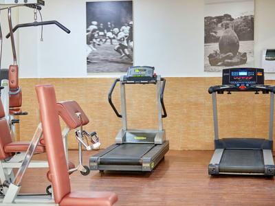 Gimnasio con dos cintas de correr y máquina de fuerza frente a fotos en blanco y negro.