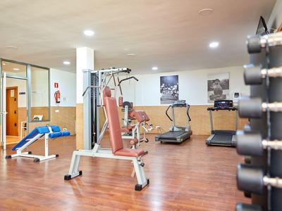 Gimnasio hotelero moderno con máquinas de ejercicio y cintas de correr sobre suelo de madera.