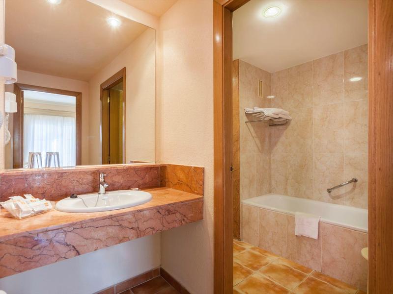 Hotel bathroom with marble sink countertop and bathtub with towel.