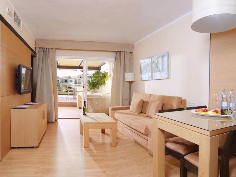 Bright living room with sofa, table, TV, and access to a terrace with plants.