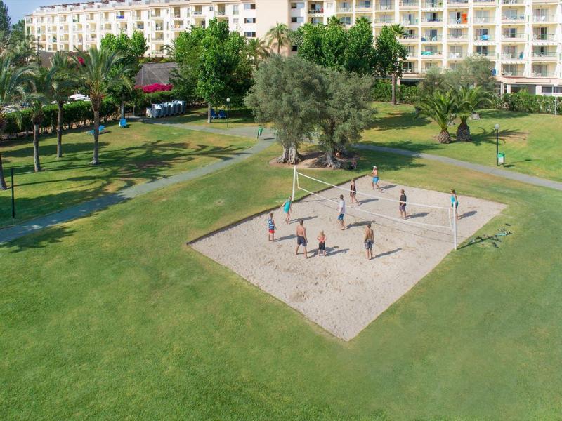Large green park with volleyball court and hotel building in the background