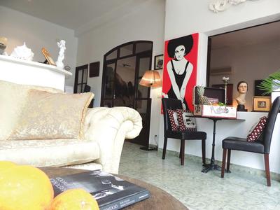 Helles Wohnzimmer mit weißem Sofa, zwei schwarzen Stühlen, dekorativer Lampe und großem Wandbild.