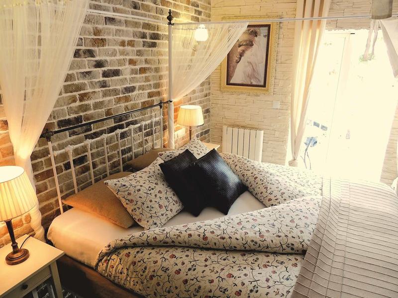 Przytulny pokój hotelowy z wzorzystym łóżkiem, poduszkami i ceglaną ścianą.