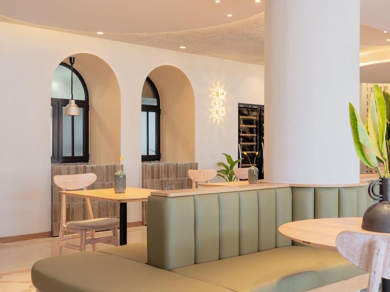 Modern lounge with curved leather sofa and round tables in bright interior.