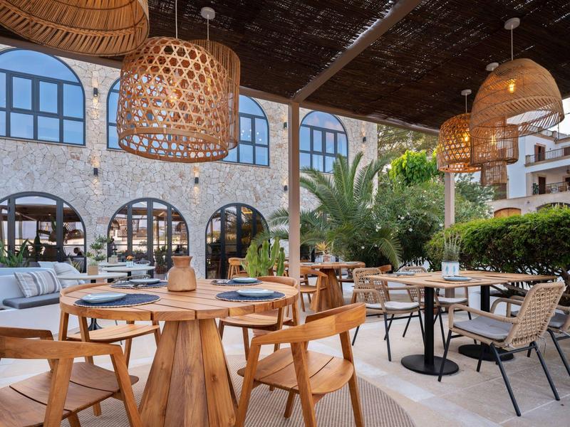 Cozy hotel outdoor area with wooden furniture, wicker lamps, and plants