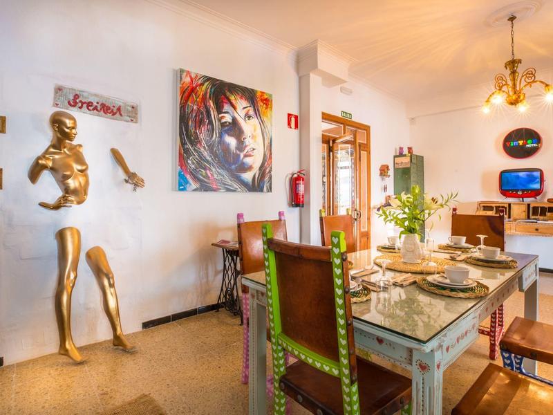 Dining room with rustic wooden table, colorful chairs, and modern art on the walls.