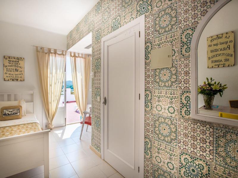 Bright hallway with decorative wallpaper, white door, and glass door leading to balcony.