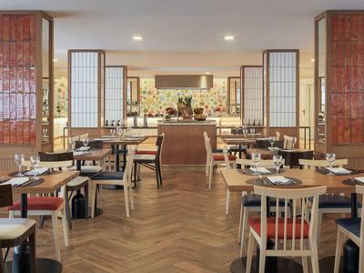 Moderne, lichte eetzaal met houten tafels en stoelen in een hotelrestaurant.