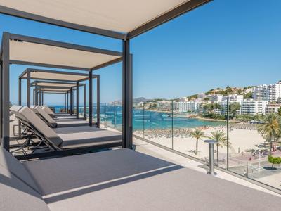 Modern hotel met ligstoelen op balkon met uitzicht op strand en stad.