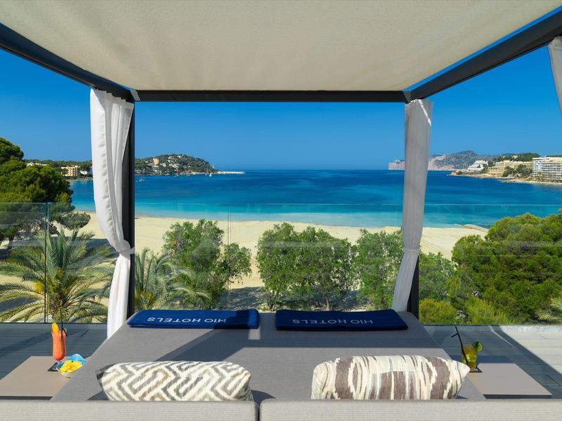 Luxe dagbedlounge met uitzicht op het strand en de zee onder een heldere blauwe lucht.