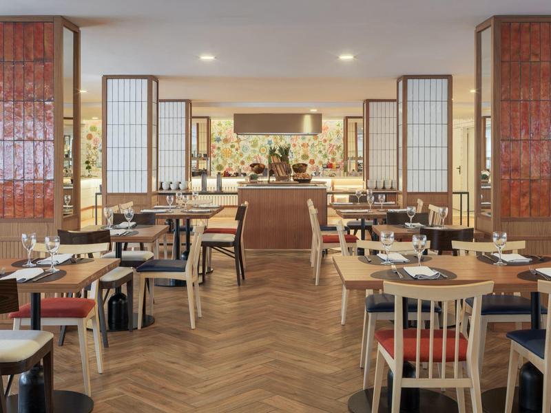 Moderne, lichte eetzaal met houten tafels en stoelen in een hotelrestaurant.