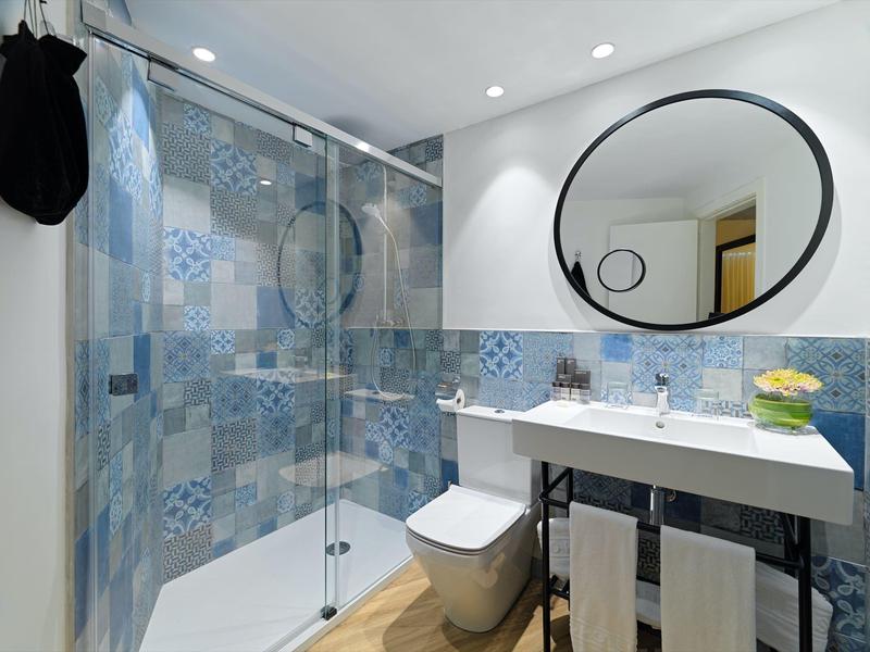 Moderne badkamer met wastafel, toilet en douche met blauwe tegels.