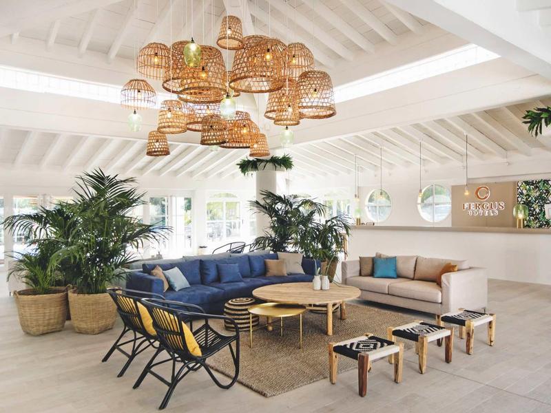 Heller Wohnraum mit hohen Decken, blauen und beigen Sofas, Holzlampen und vielen grünen Pflanzen.