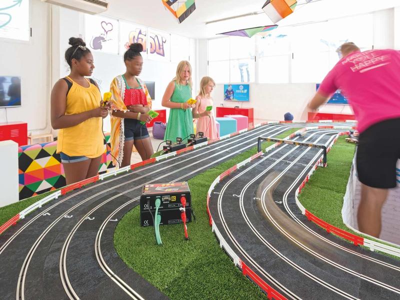 Kinder und Erwachsener spielen gemeinsam an einer großen, mehrspurigen Slotcar-Rennbahn.