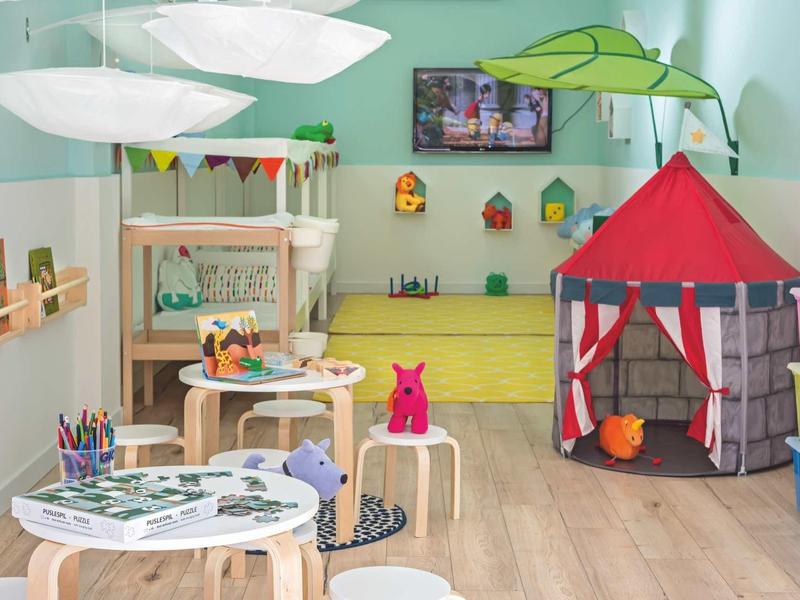 Buntes Kinderzimmer mit Spielzelt, Malutensilien, Teppich und fröhlicher Wandgestaltung.