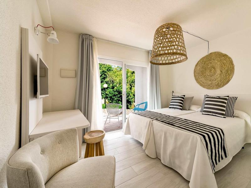 Gemütliches Schlafzimmer mit Doppelbett, hellen Wänden, Balkon und Korblampe.