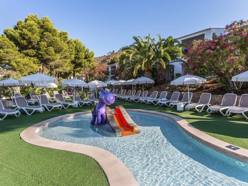 Kinderplanschbecken mit lila Elefantenrutsche, umgeben von Liegestühlen und Sonnenschirmen.