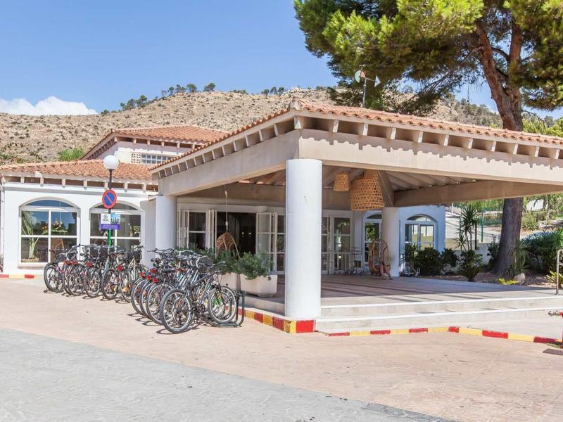 Ein heller Eingangsbereich eines Gebäudes mit Fahrrädern und einem begrünten Hügel im Hintergrund.