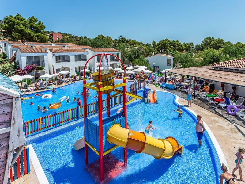 Buntes Freibad mit Rutschen, Wasserattraktionen und Liegestühlen bei sonnigem Wetter.